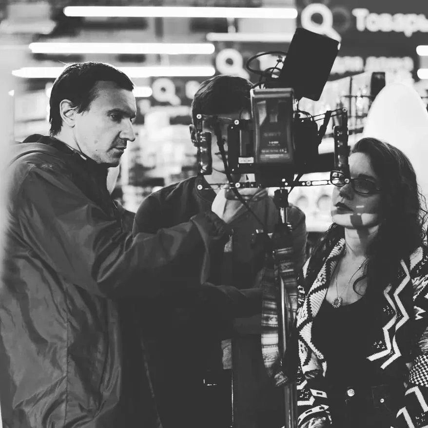 Roman discusses the shot with two crew members beside the camera.