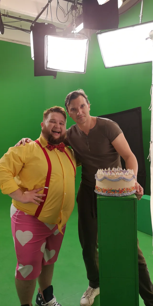 Roman and the lead performer Pukhlya beside a cake on the green-screen stage.